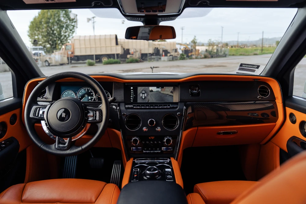 Rolls-Royce Cullinan Black Badge luxury interior with steering wheel, dashboard and orange leather trim