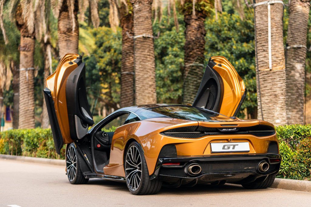 Copper-orange McLaren GT rental in San Diego - rear three-quarter view with dihedral doors open
